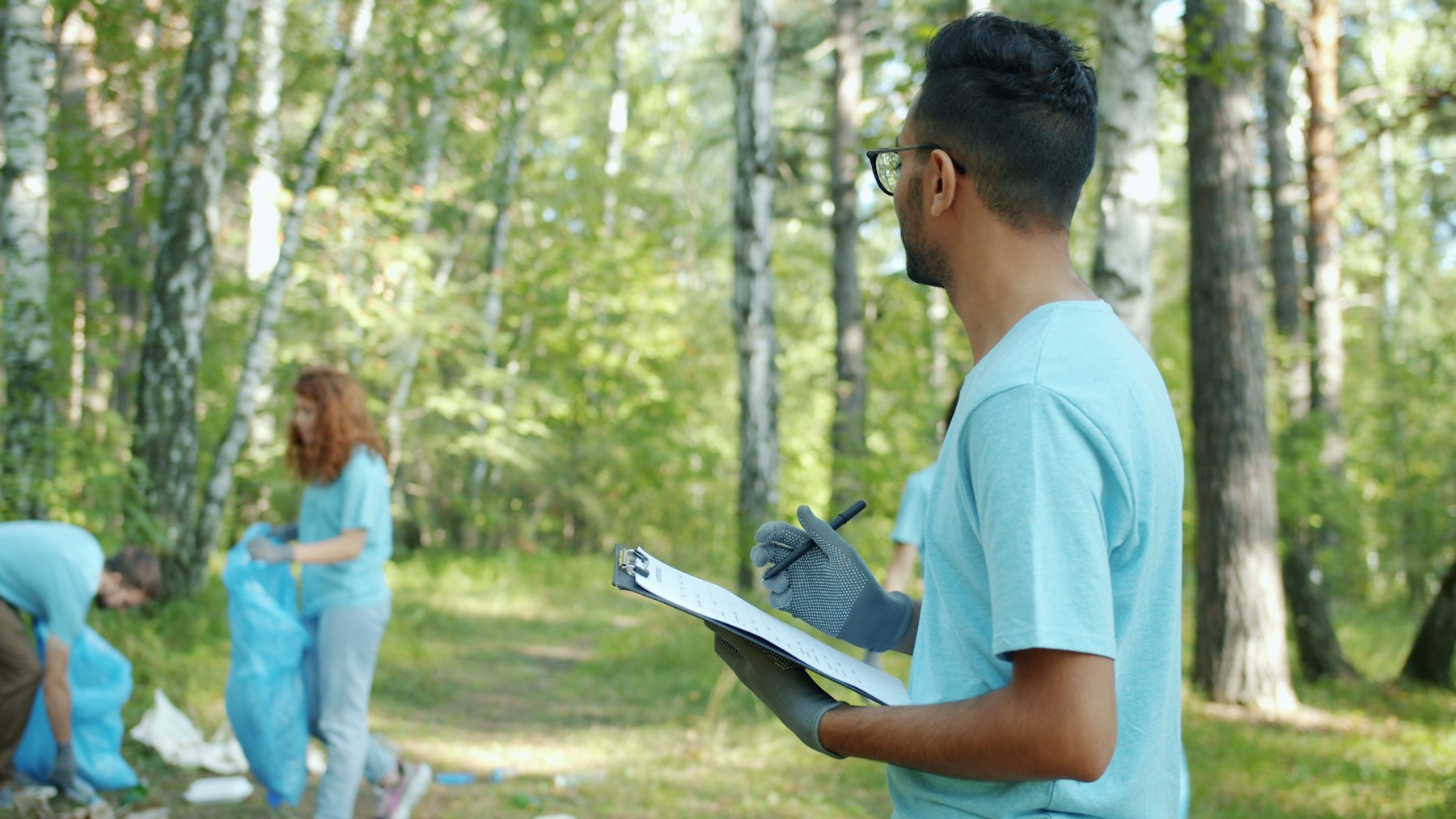 A volunteer crew lead with a clipboard during a park clean-up