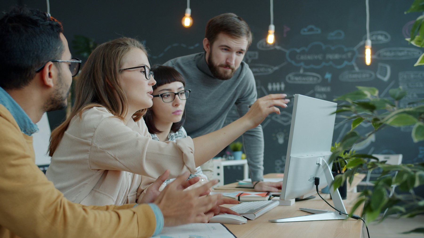 A small team gathered around a computer, talking through a plan